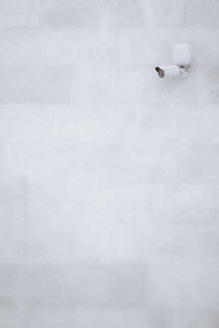 A minimalist shot of a surveillance camera against a concrete wall with ample copy space.